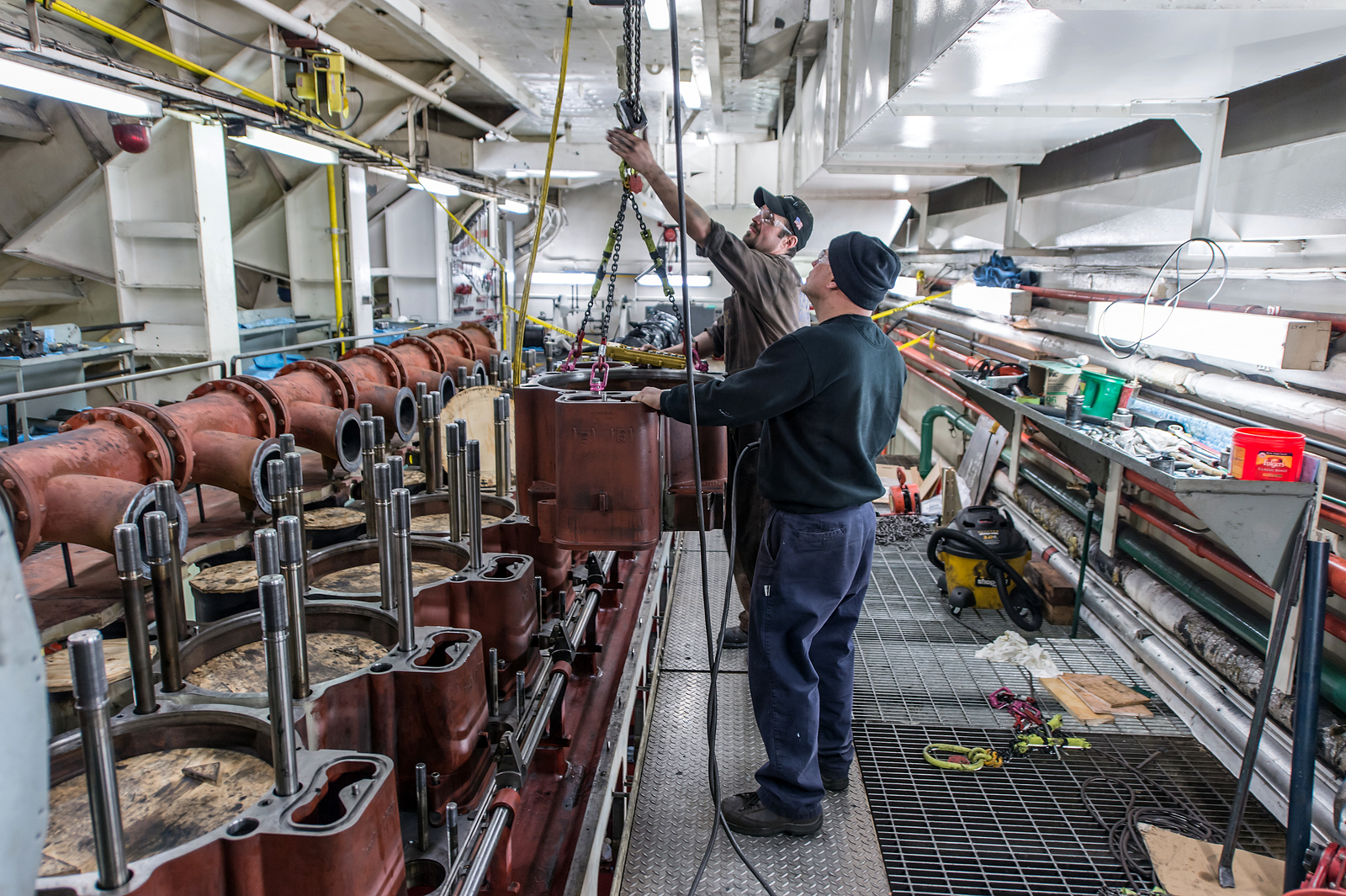 On the Edwin H. Gott, Michael Kolenda (foreground), Great Lakes Fleet engineer, and Aurel Carina, MaK service engineer, remove heads from the starboard main engine as it undergoes a complete overhaul, part of routine winter maintenance. Credit: Robert Welton