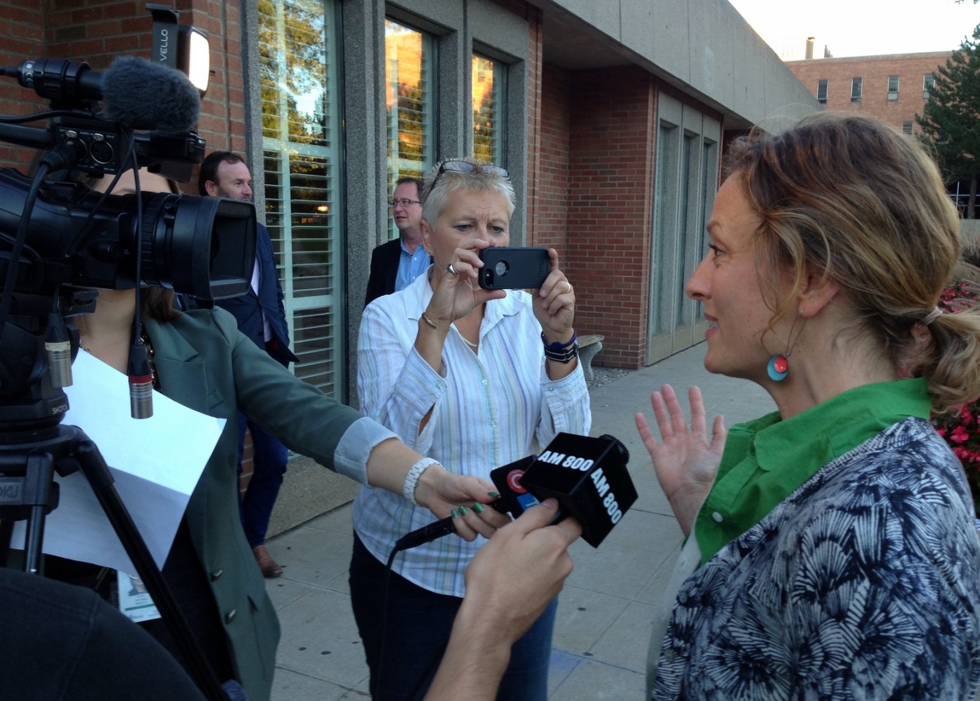 Sarah Harmer (à droite) s’adresse à des reporters, à l’extérieur du forum.